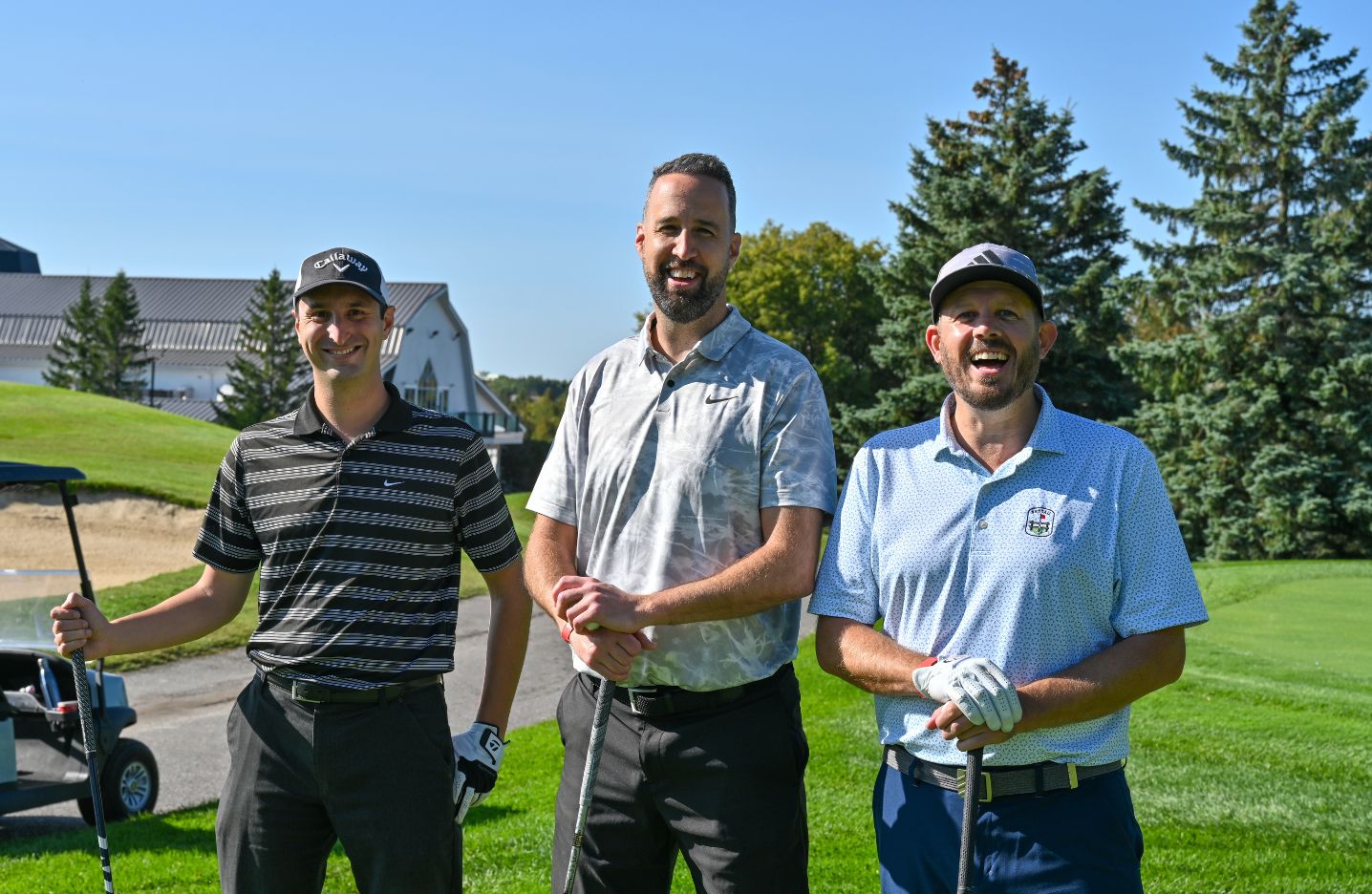 Three men golfing at a tournament smiling