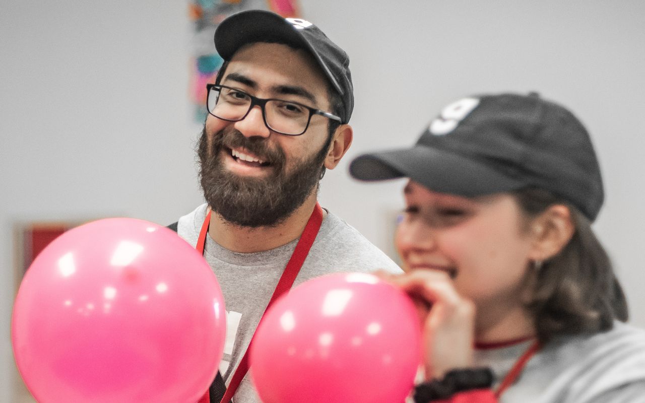 Two staff individuals blowing up ballons